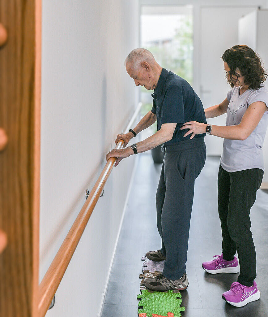 Physiotherapeutin erklärt einem Bewohner den Ablauf von Koordinationsübungen.