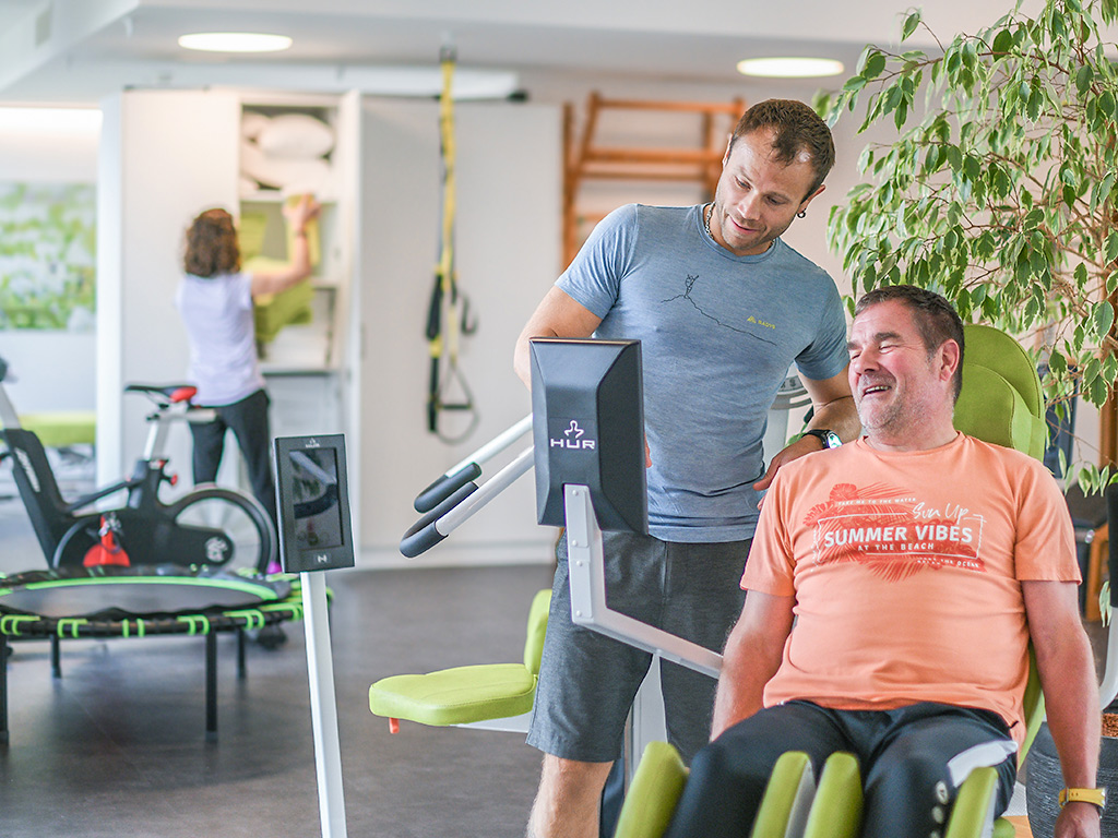Physiotherapeut oder Trainer erklärt einem Patienten den Ablauf und die Übungen des Trainings.